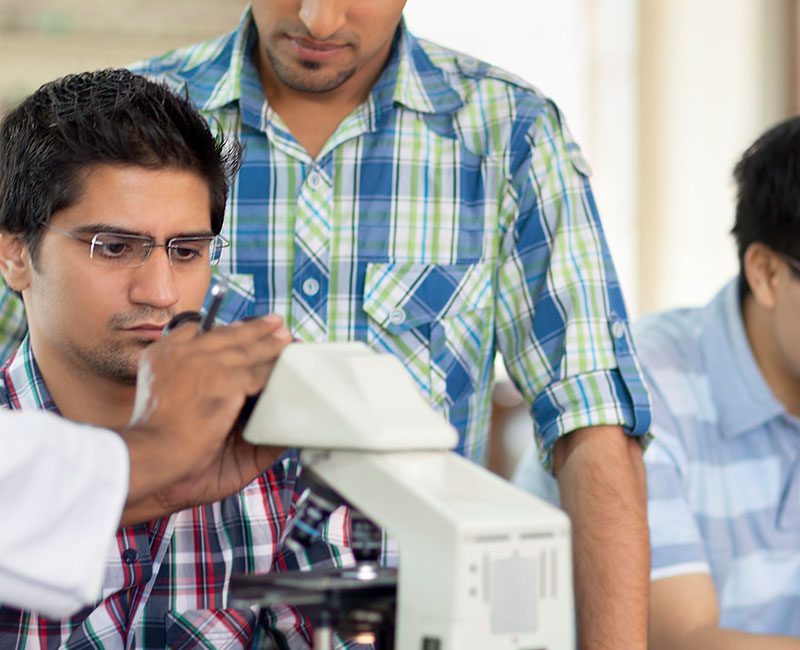 Group of scientists exploring through microscope