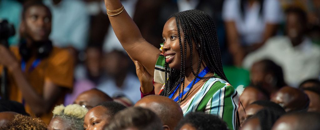 Young woman with hand in the air at conference