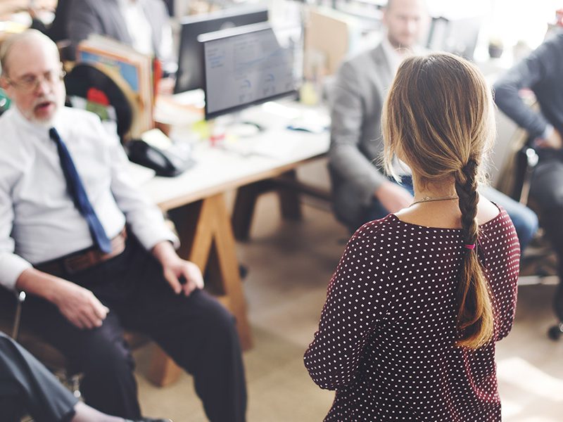 Young woman speaking in front of group of people