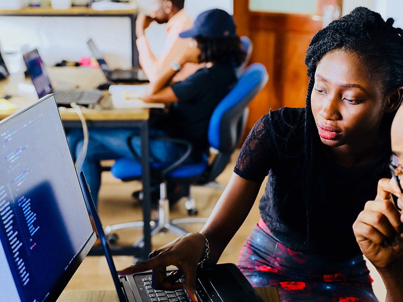 Two young African workers discussing work on screen