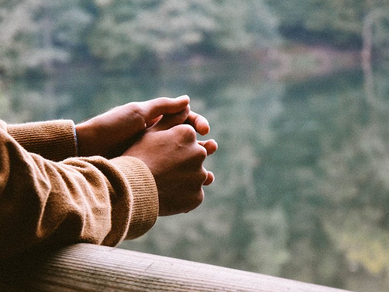 Man leans with hands over balcony