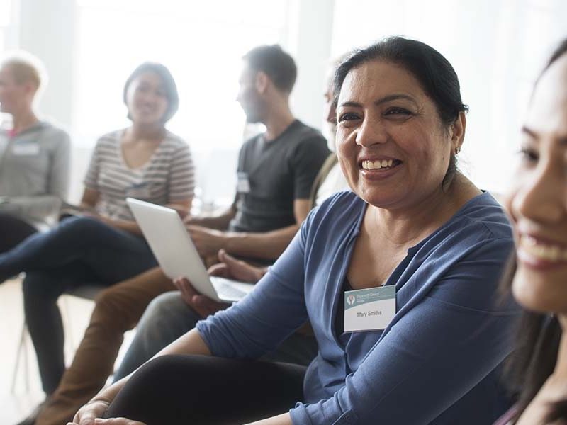 Two women smiling sat in circle with group