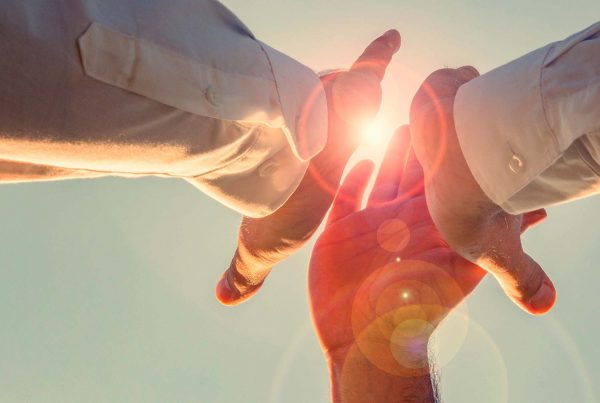 Three people high fiving with hand glowing through light
