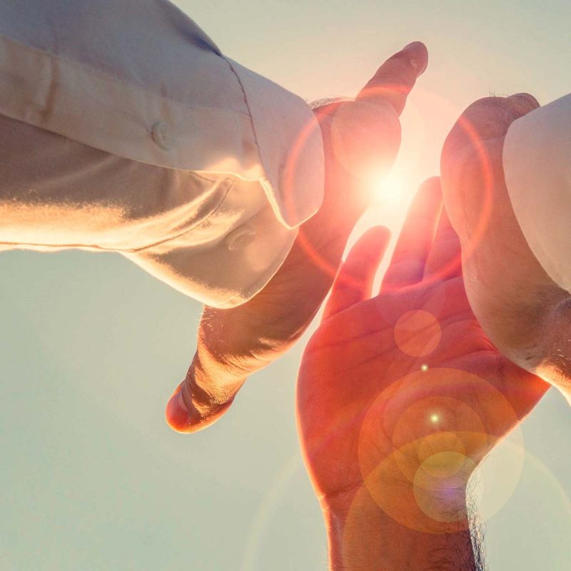 Three people high fiving with hand glowing through light