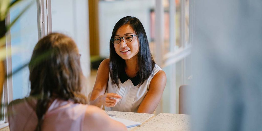 Two woman sat at a meeting discussing work