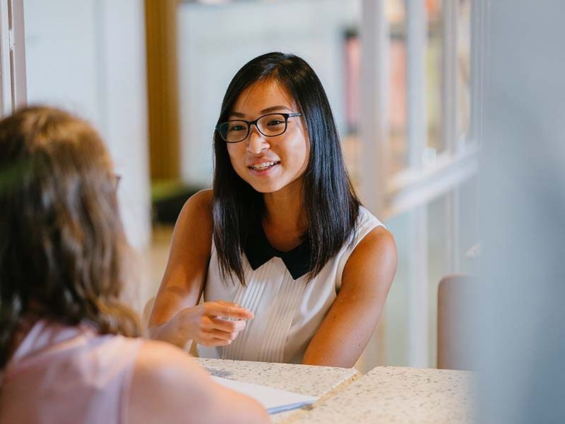 Two woman sat at a meeting discussing work