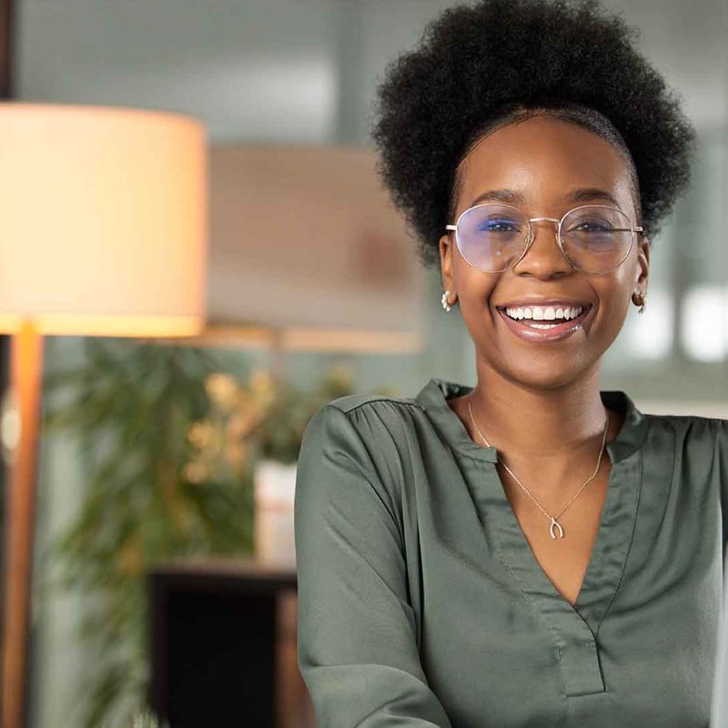 Young woman smiling and looking at camera while working on laptop