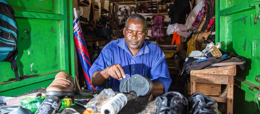 Shoemaker repairing shoe in his store