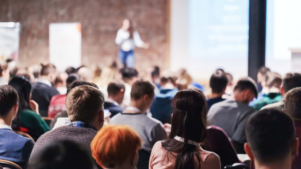 Woman presenting to large room of people