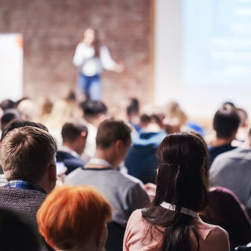 Woman presenting to large room of people