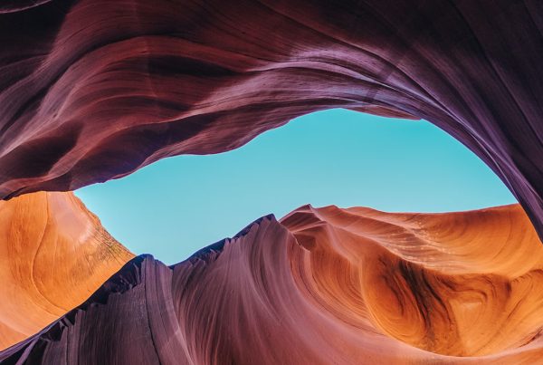 Looking up at a swirling rock formation, with the blue sky visible in the middle