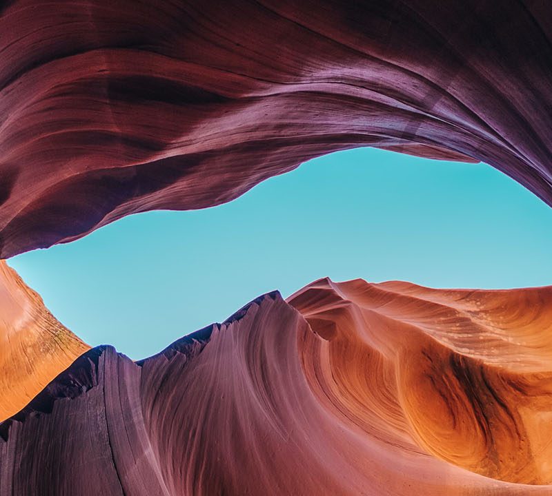 Looking up at a swirling rock formation, with the blue sky visible in the middle